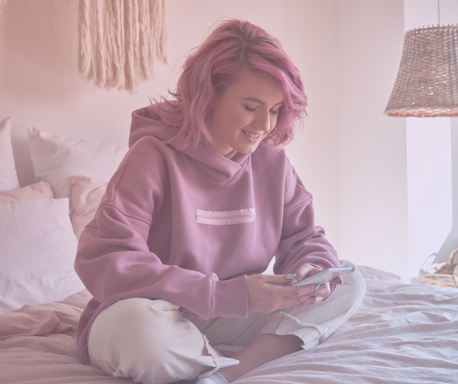 Gen Z college student with pink hair smiling at cell phone